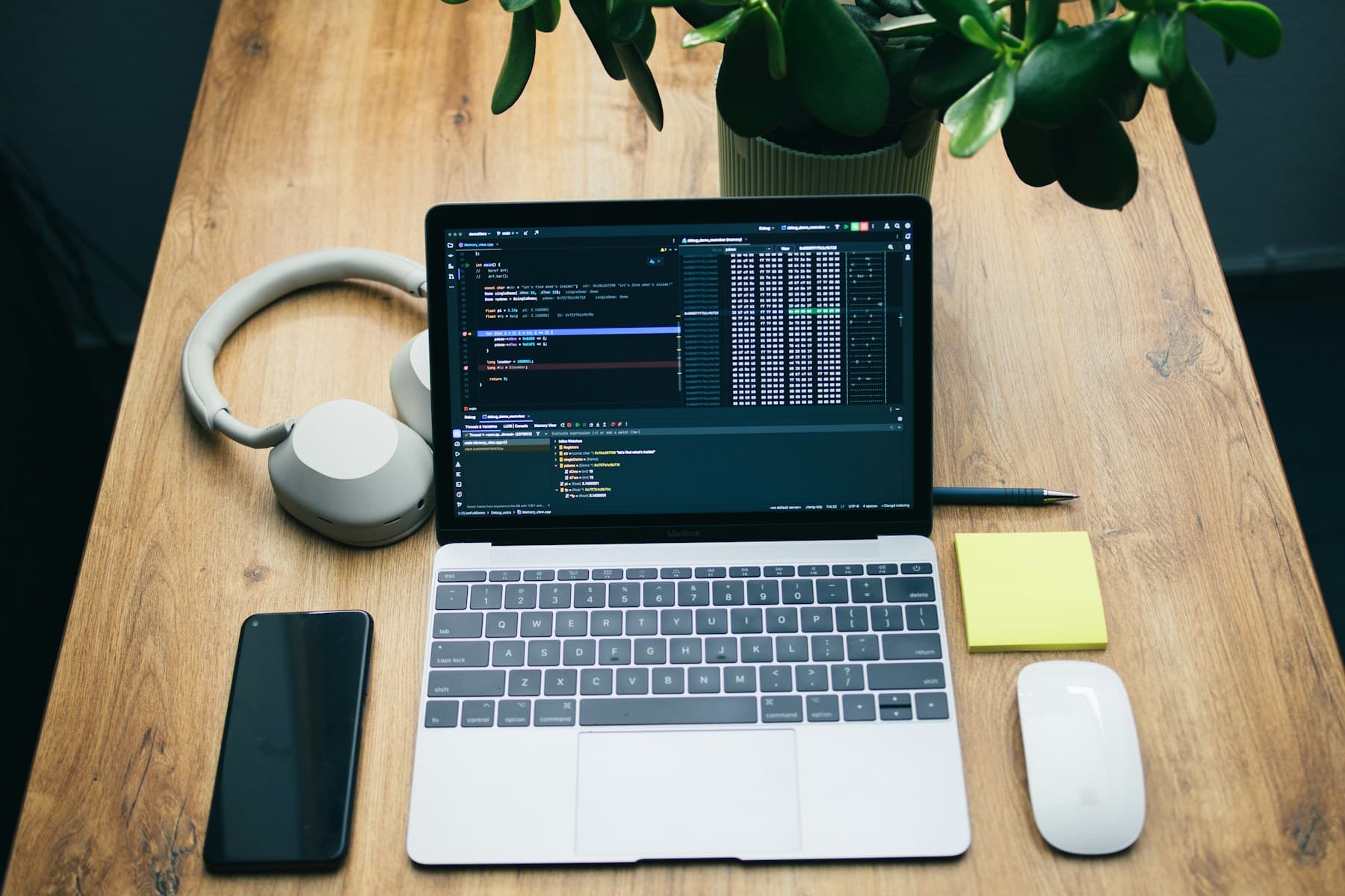 Developer workspace with laptop, code editor, phone, and desk tools